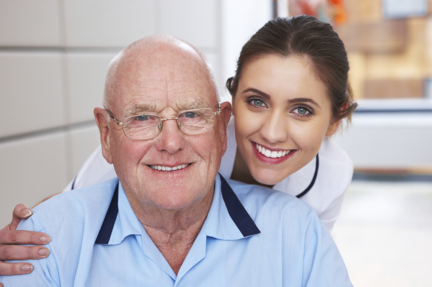 Attractive nurse and her elderly patient smile together for the camera. Horizontal shot.